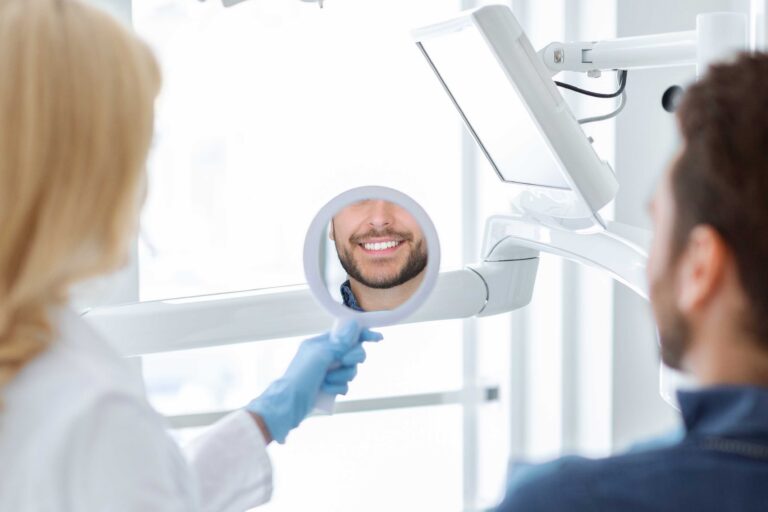 Dental patient looking into a mirror held by the dentist.